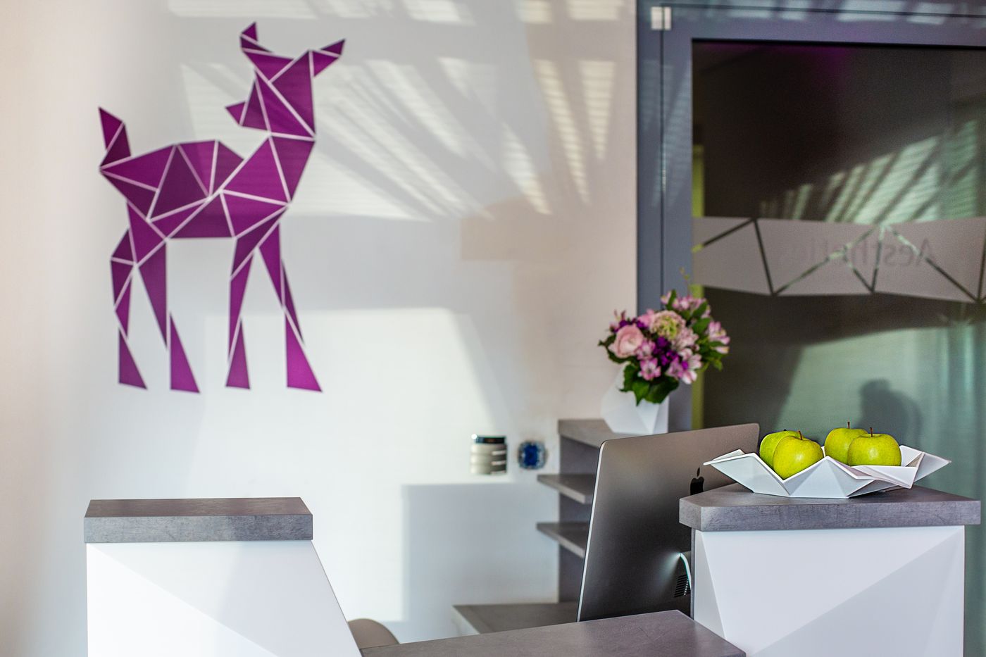 Empfangsbereich mit violettem Reh-Motiv an der Wand und Blumenstrauß